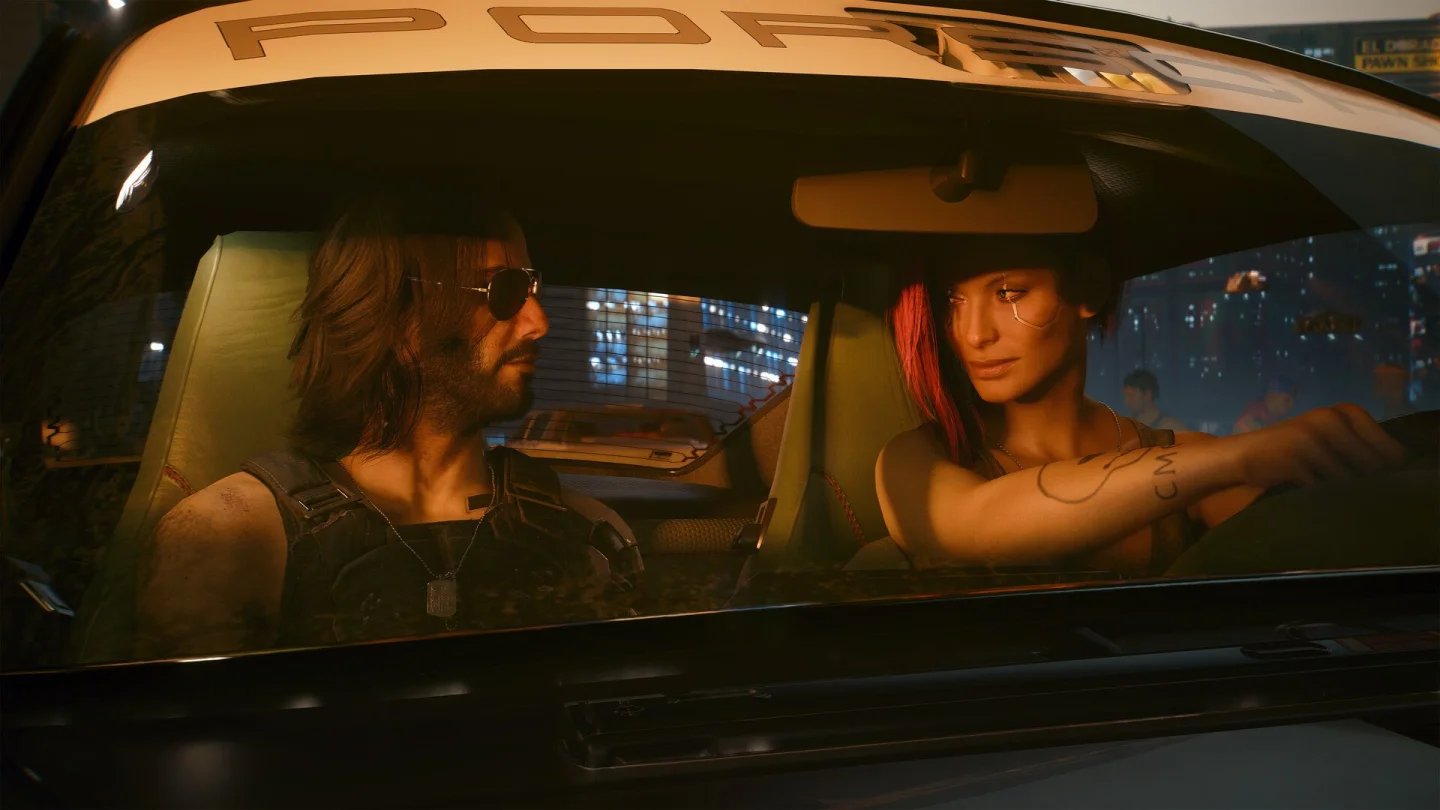 Cyberpunk 2077'den Night City'de araba içinde iki karakterin yer aldığı sahne